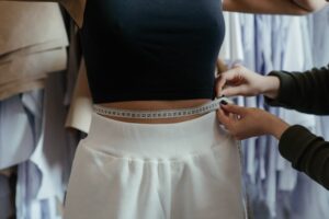 Tummy tuck concept. A tailor measuring a woman's waist.