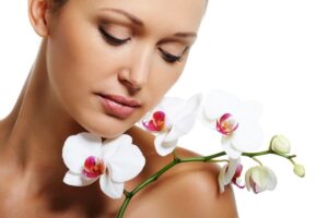 Face of pretty beautiful woman with a white orchid on her shoulder